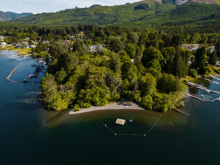 A square floating dock, floating just off the shore on Cowichan Lake, is surrounded by a floating border
