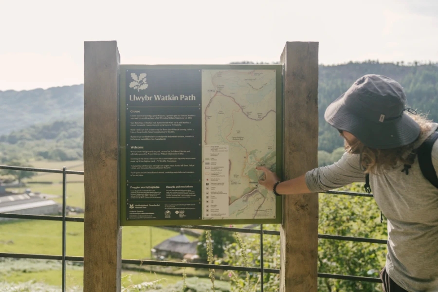 A man points to a trail on a map on the trail Sign of llwybr Watkin Path
