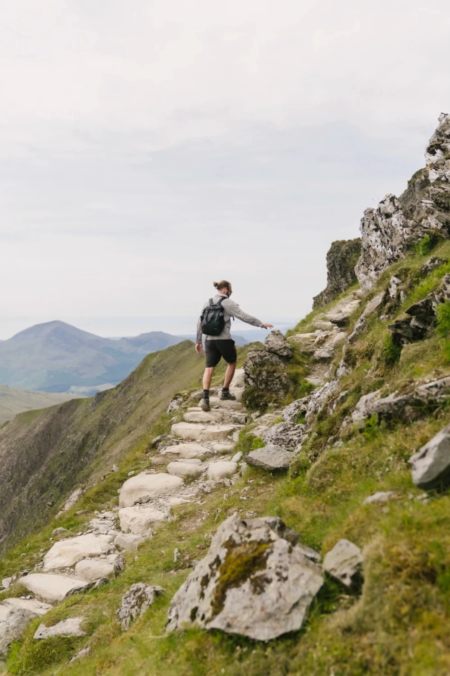 A man walking up stone stairs near the peak of Mount Snowdon