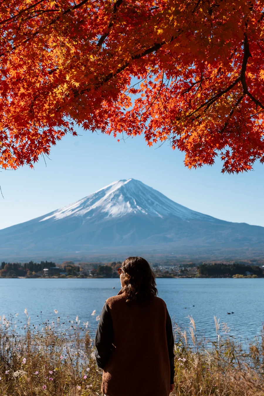 Woman standing in front of the snow capped peak of Mt Fuji seen from Oishi Park