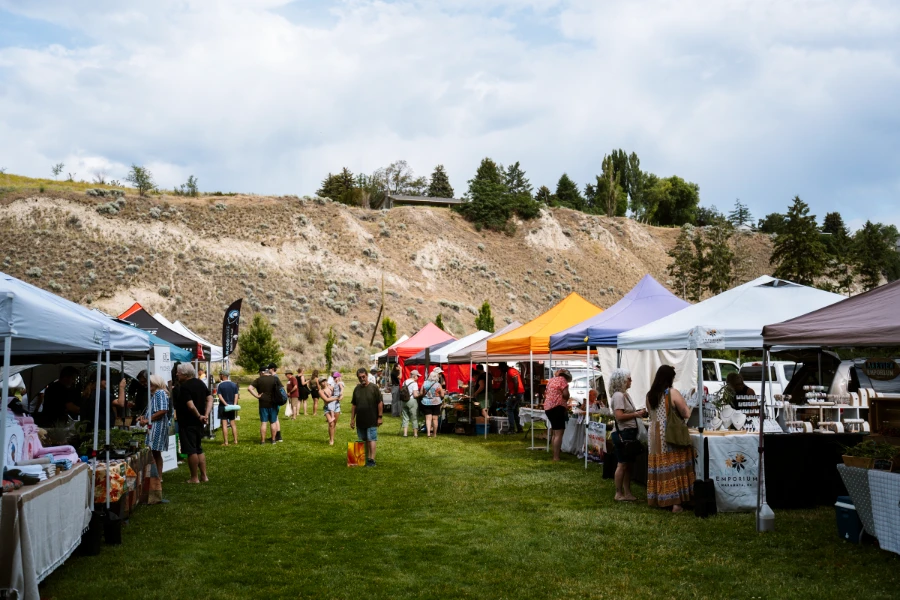 Rows of market stalls line a grassy area in Naramata selling a wide variety of farmers’ market goods.