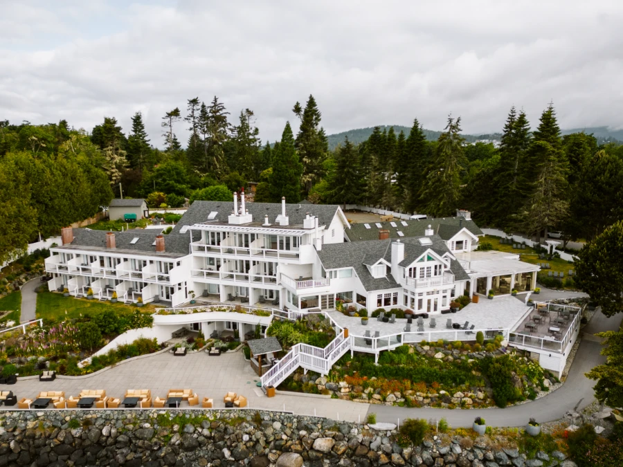 A large white wooden hotel with a large patio on the waterfront