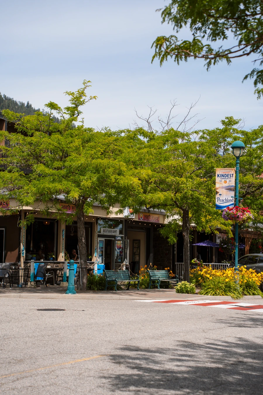 A small restaurant facade across the street on a tree-lined street in Peachland