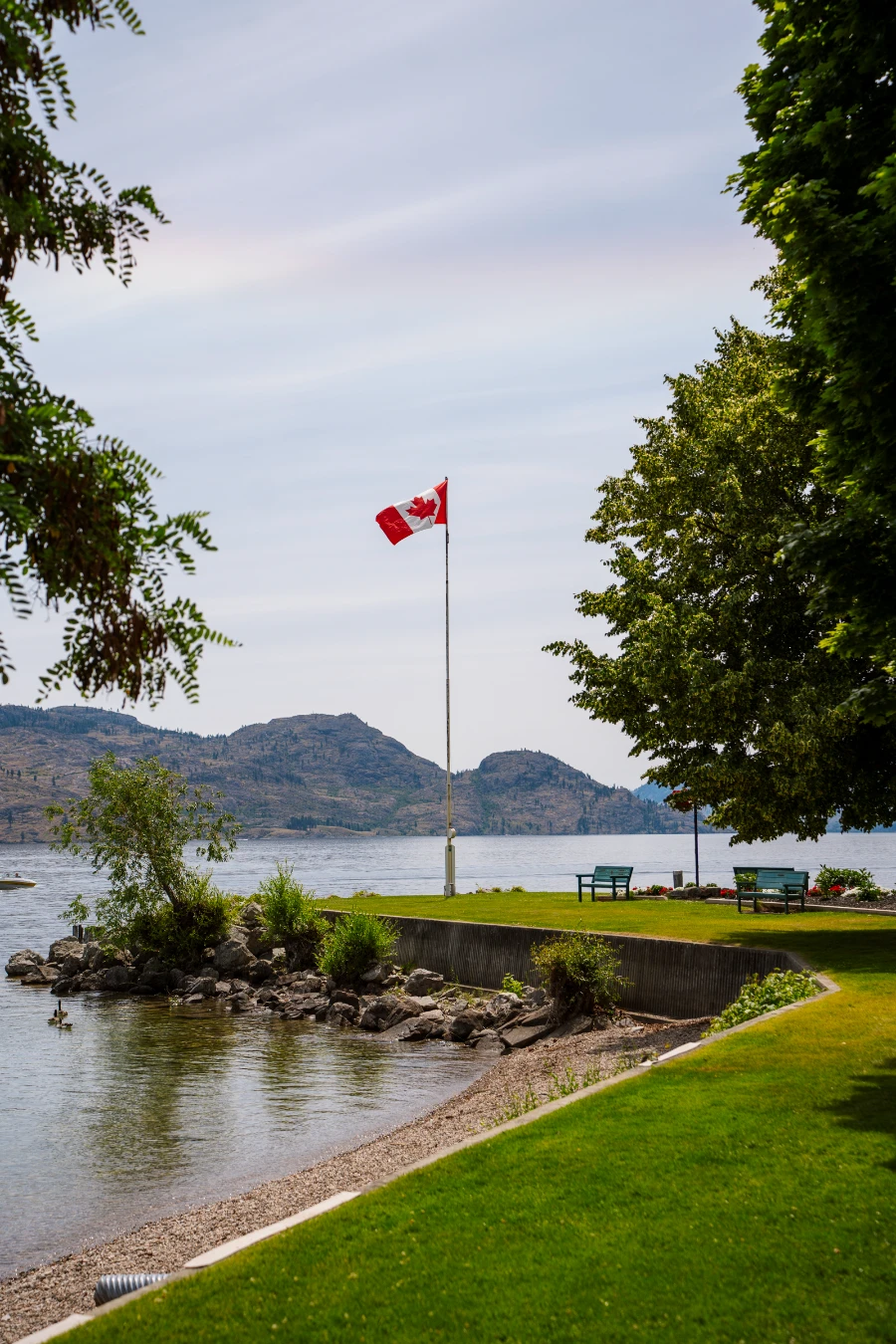A manicured lawn curves around to a small peninsula with a Canadian flag hanging