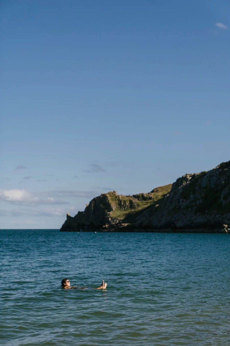 A woman floating in the sea near Barafundle Bay, Wales