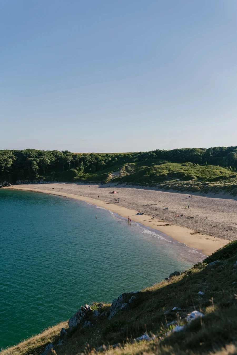 Calm waves roll into a sandy bay bordered on all sides by large cliffs