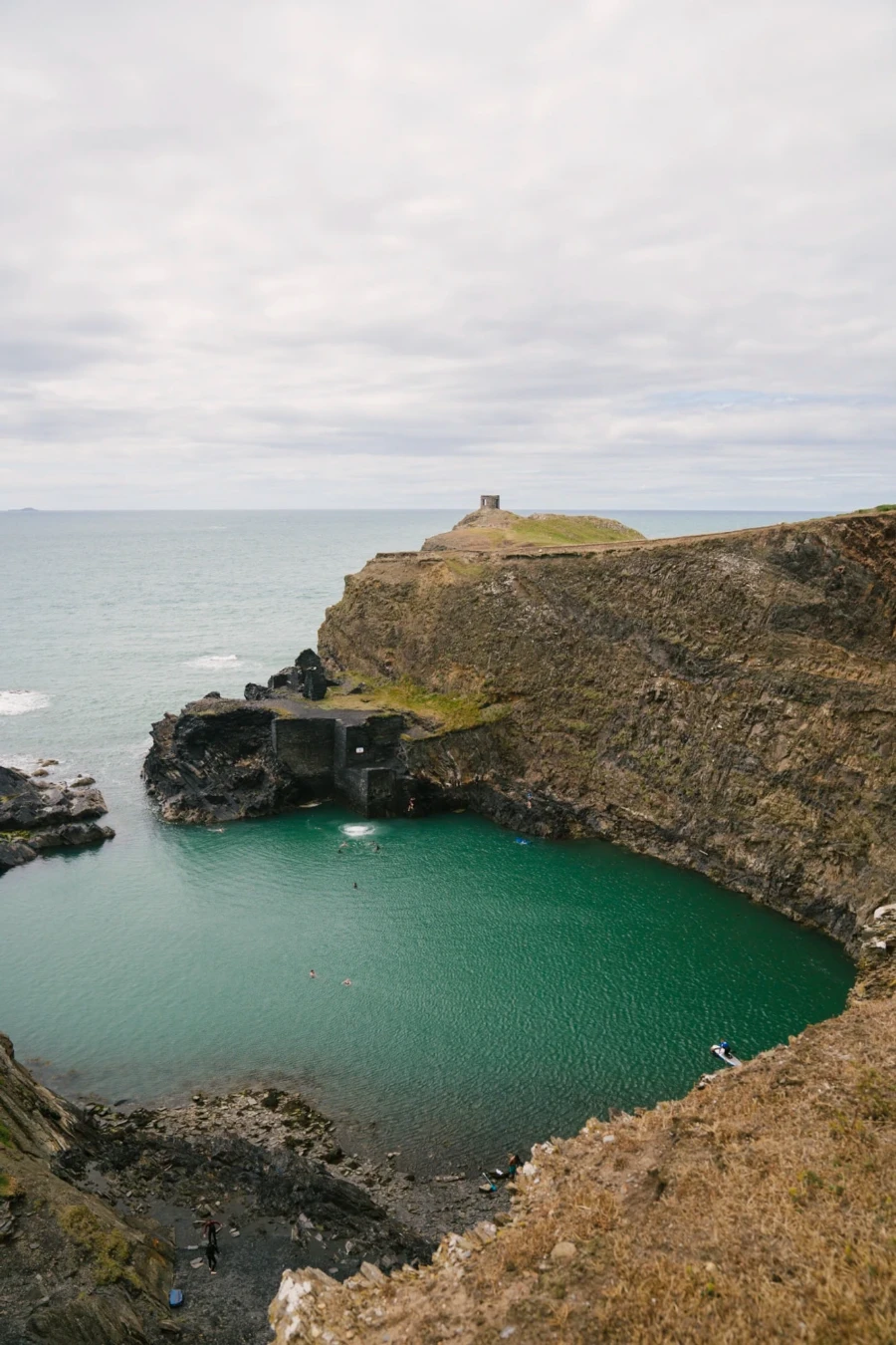 A circular body of water surrounded on all sides by cliffs except for a small gap in the rocks where it connects with the sea