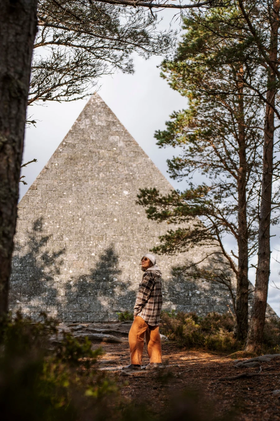 woman stands in front of Prince Albert's Cairn, a large stone pyramid