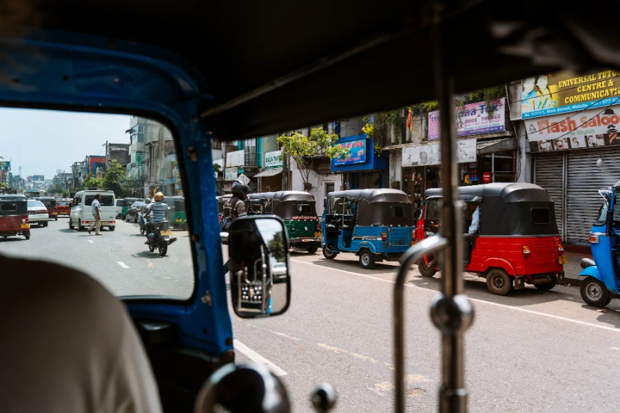 line of tuktuks parked along the road in a busy city in Sri Lanka