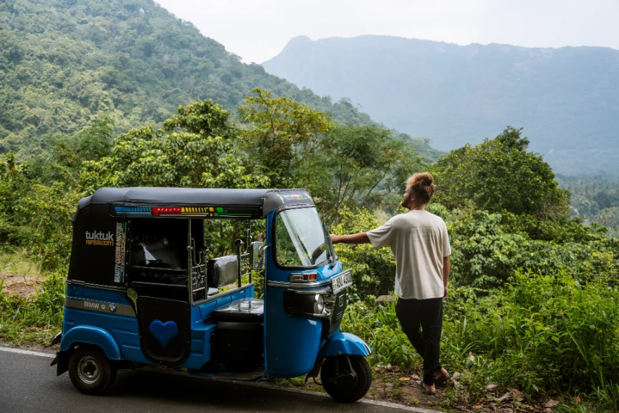 Man stands with a tuktuk looking out to the jungle