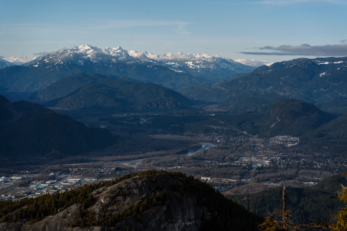 A distant view of a dry Squamish Valley with the snowy peaks of the Tantalus range in the distance