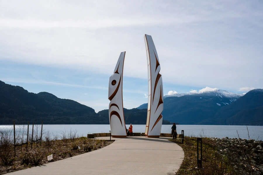 A stone path leads to two indigenous monuments at the edge of the Howe Sound in Squamish surrounded by mountains