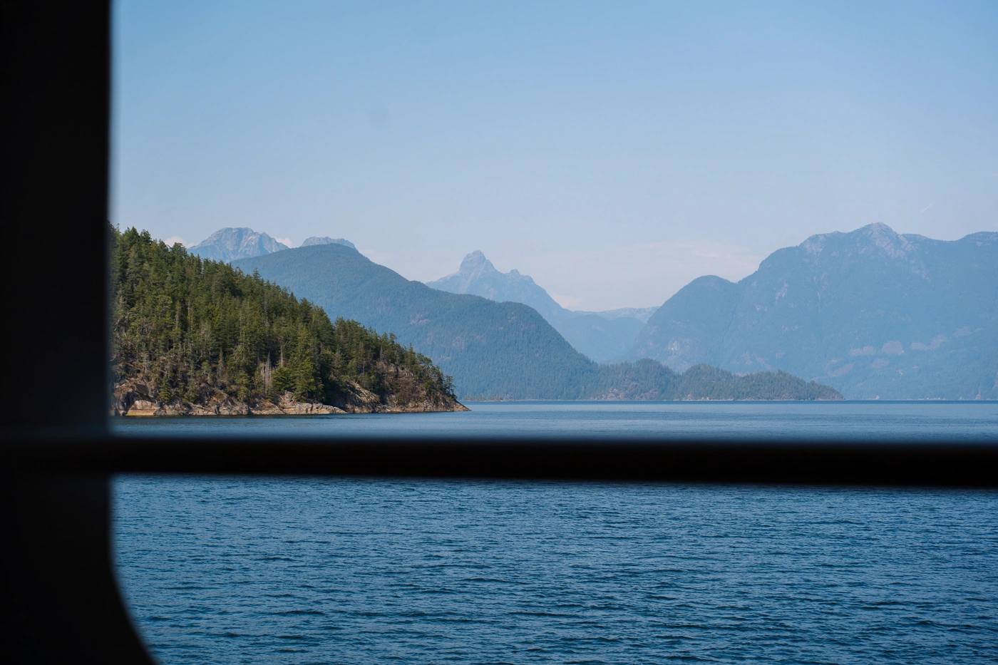 Rocky islands covered in trees framed through a BC ferry window