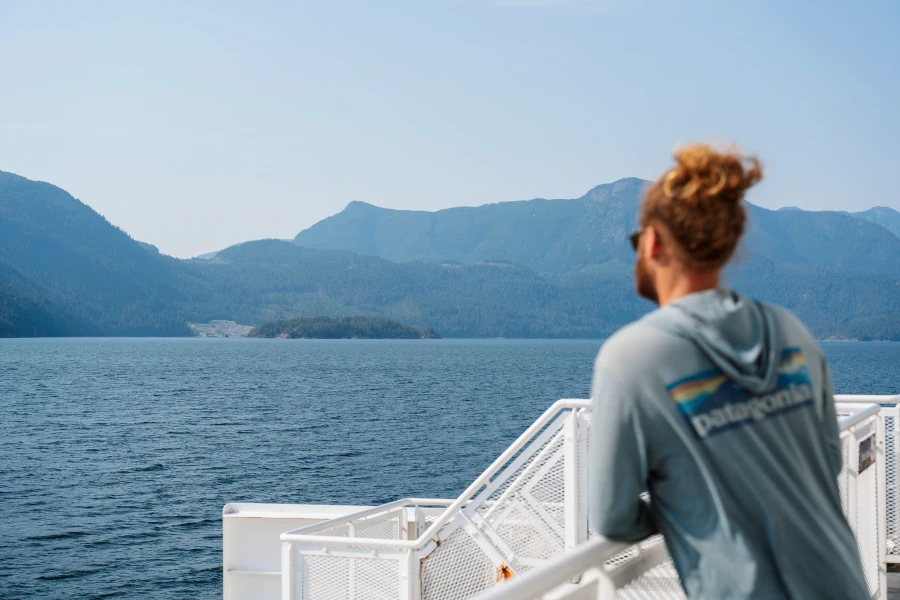 Man leaning on the railing of a BC ferry looking across at the Sunshine Coast