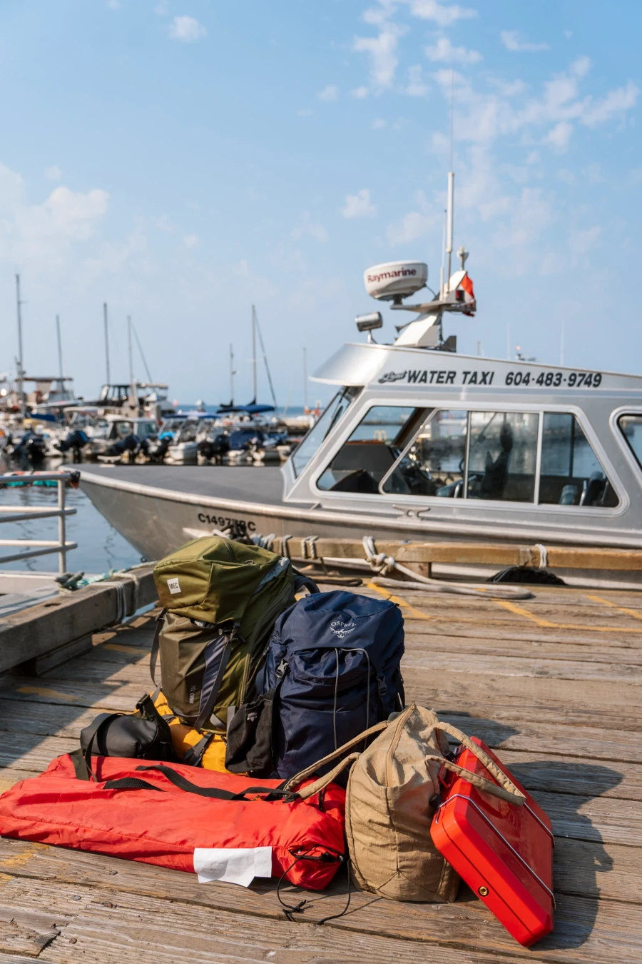A collection of bags and camping gear scattered on a wooden dock