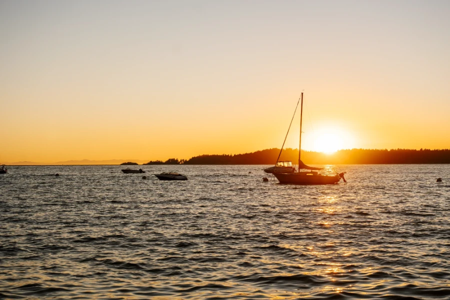 Last moments of sunset illuminate an anchored sailboat in Tunstall Bay