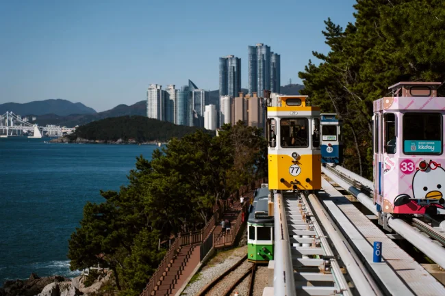 Colorful sky pods ride along rails next to the ocean in Busan, South Korea