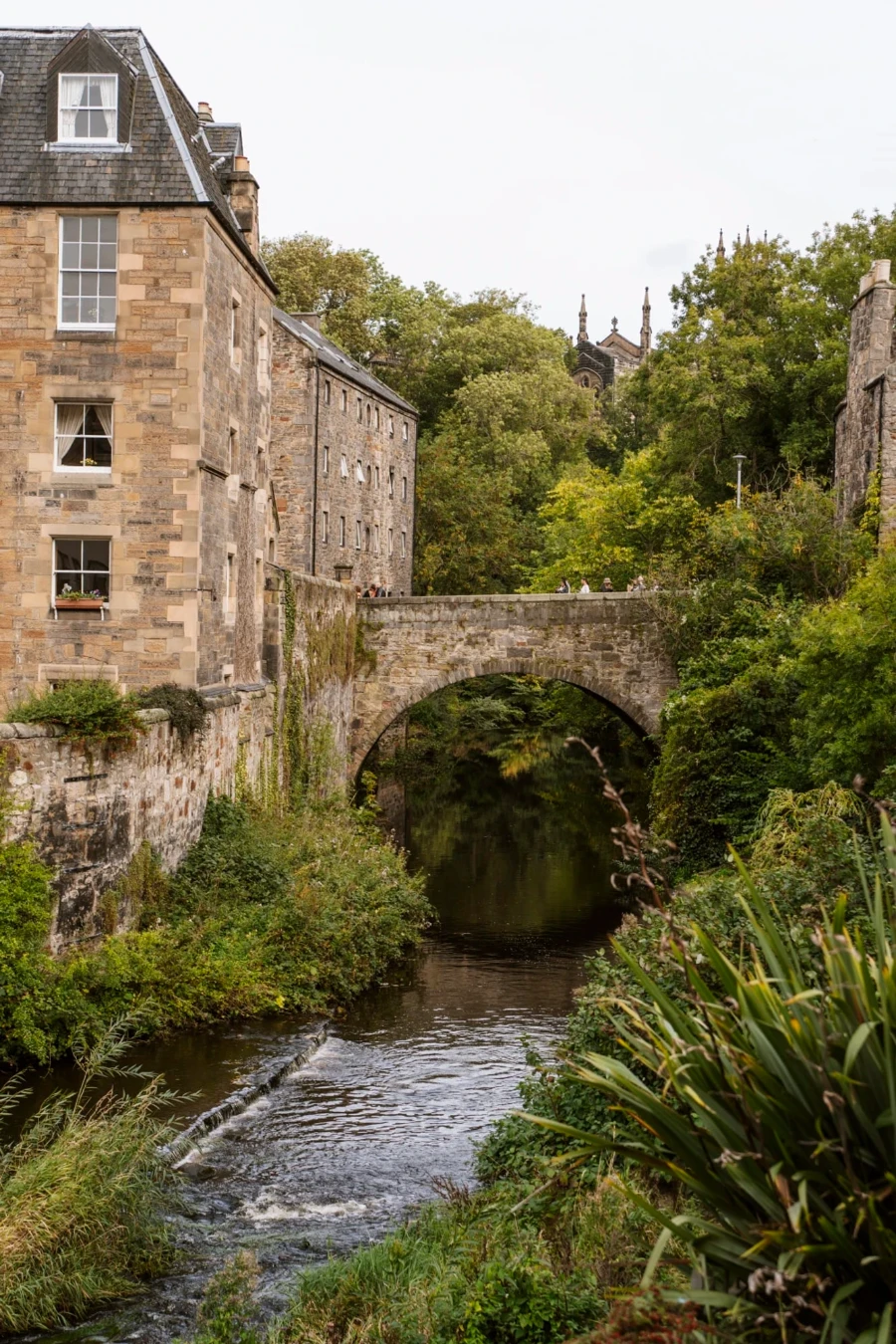A stone arch bridge crosses over the Water of Leith in Edinburgh, Scotland