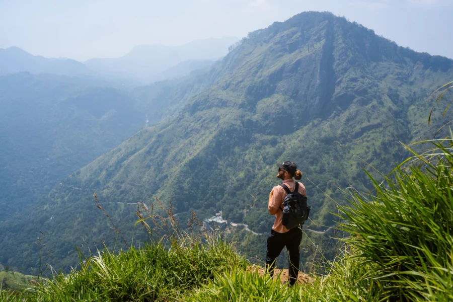 Man stands on the edge of a cliff near Little Adam's Peak looking down at the jungle valley below
