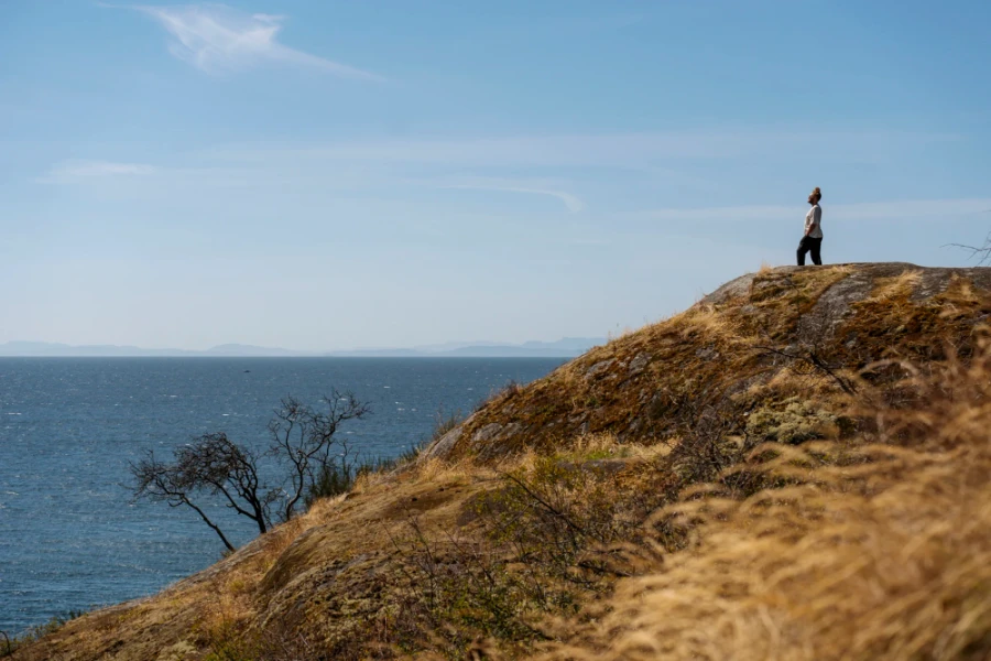 man stands atop Gospel Rock with Vancouver Island visible on the horizon