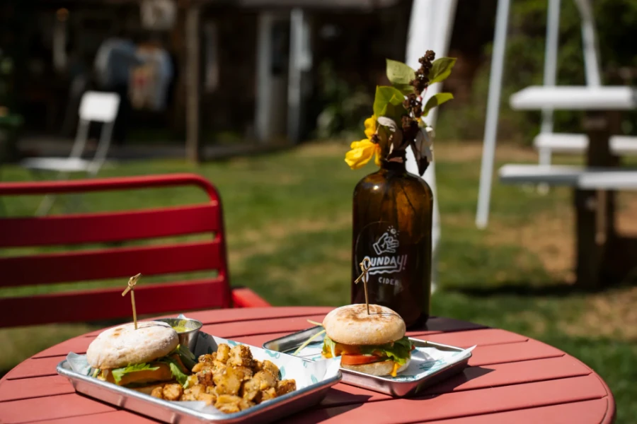Breakfast sandwiches and potatoes on a red patio table at Sunday Cider near Gibsons, BC.