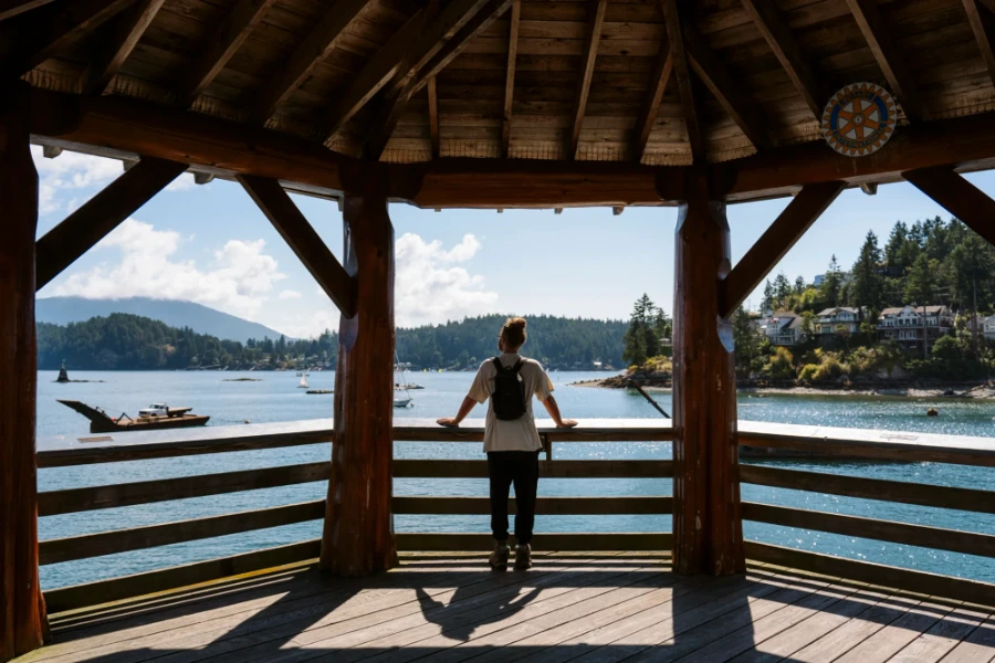 Man stands at the end of Gibsons Harbours pier looking out to sparkling water and ocean-front cottages