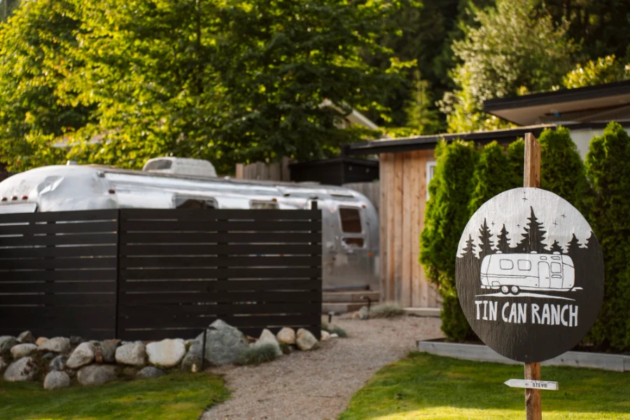 A sign reads Tin Can Ranch in front of a path that leads to an old silver airstream