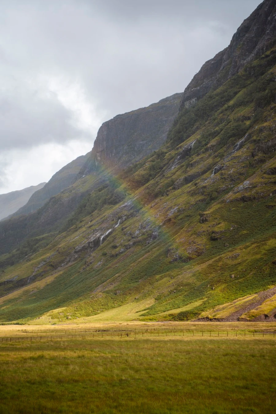 A rainbow crosses the sky over the green valley near Loch Achtriochtan