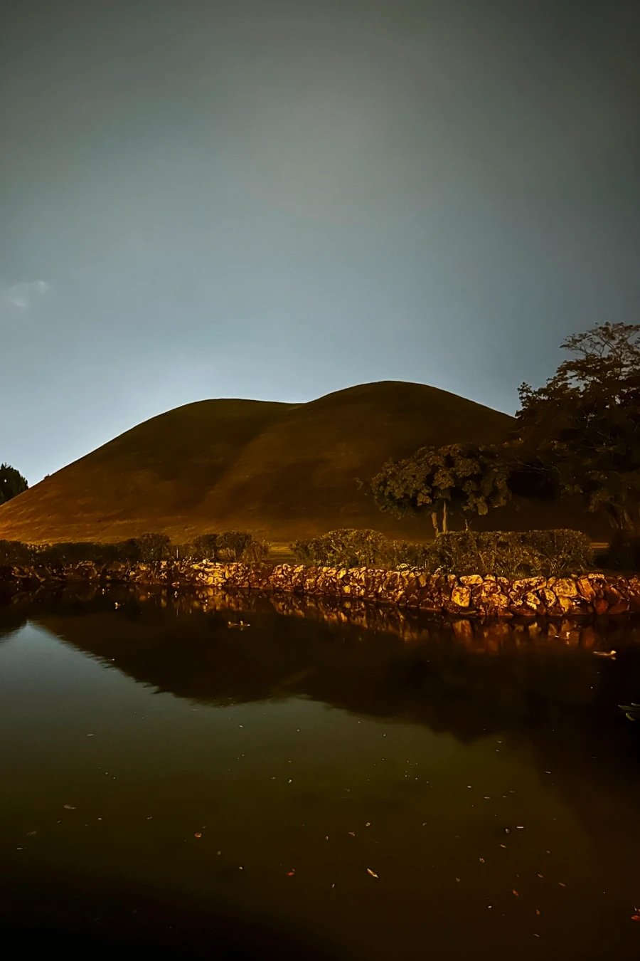 A still pond reflects the rolling hills of Daereungwon Tomb Complex