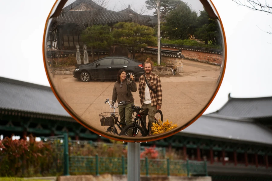 Two tourists on pedal bikes are reflected in a circular traffic mirror in Gyeongju, South Korea