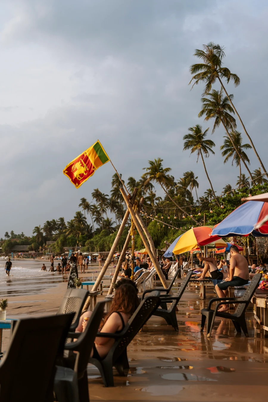 A woman sits on a chair on a wet beach near Hiriketiya Beach