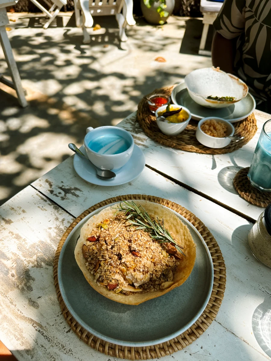 A breakfast hopper sits on a plate next to an unusual looking blue coffee