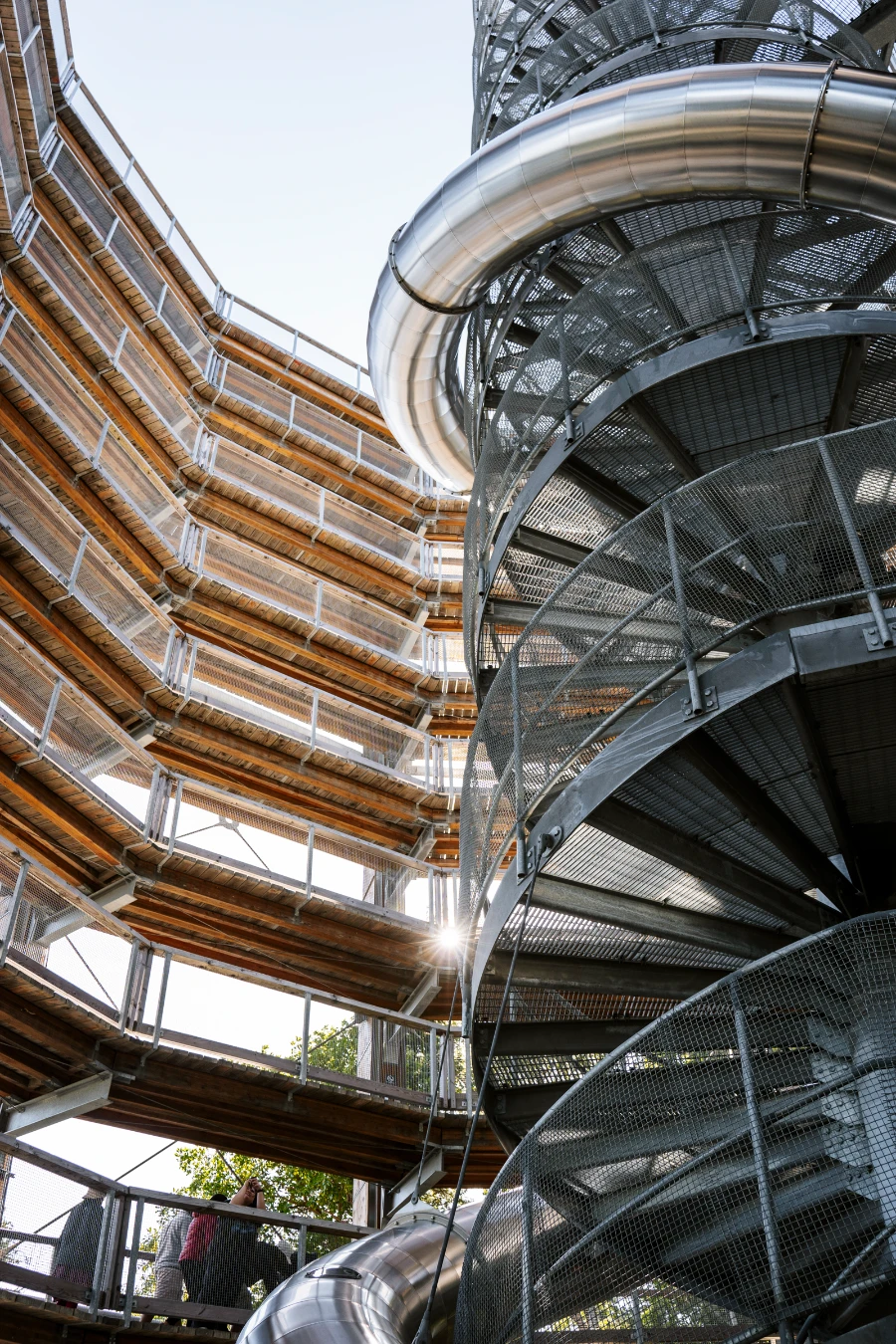 Sunflare shines through the levels of the sloped walkway of the Malahat Skywalk and the spiral metal staircase at its center