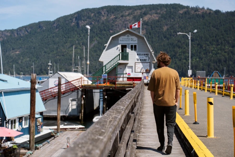 A man walks down a pier at Cowichan Bay with interesting houseboats docked beside the pier