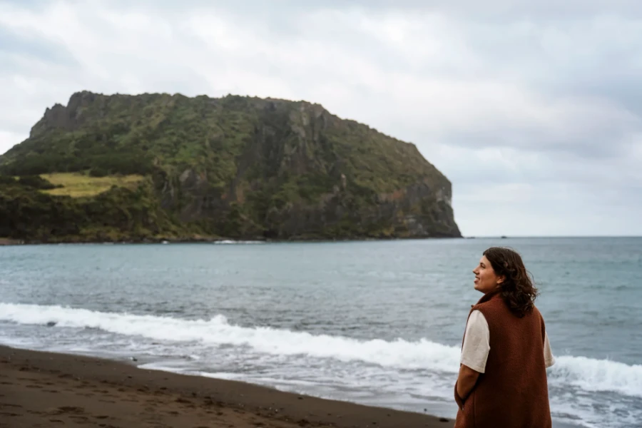 Woman walking along the wet sand of Gwangchigi Beach while gentle waves approach the shore