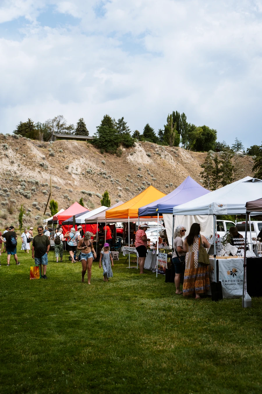 Rows of market stalls line a grassy area in Naramata selling a wide variety of farmers’ market goods.