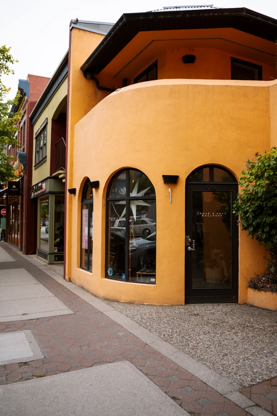 An empty sidewalk in Penticton that passes several colourful storefronts.