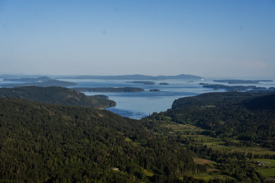 Green forest and lush farmland stretch across Salt Spring Island with other Gulf Islands visible on the horizon