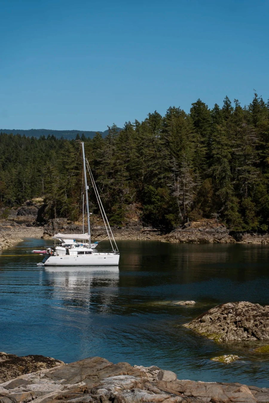 A white sail boat anchored in Smugglers Cove near Sechelt BC