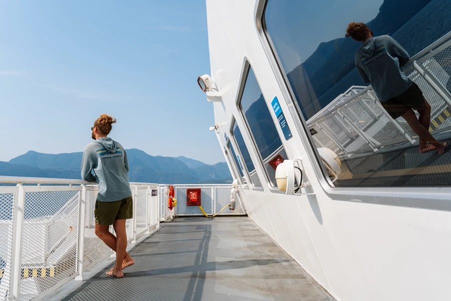 Man leans on a railing on a BC ferry near the Sunshine Coast, BC