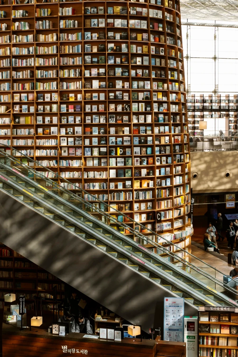 An escalator cuts across a massive bookshelf in Starfield Library, Seoul