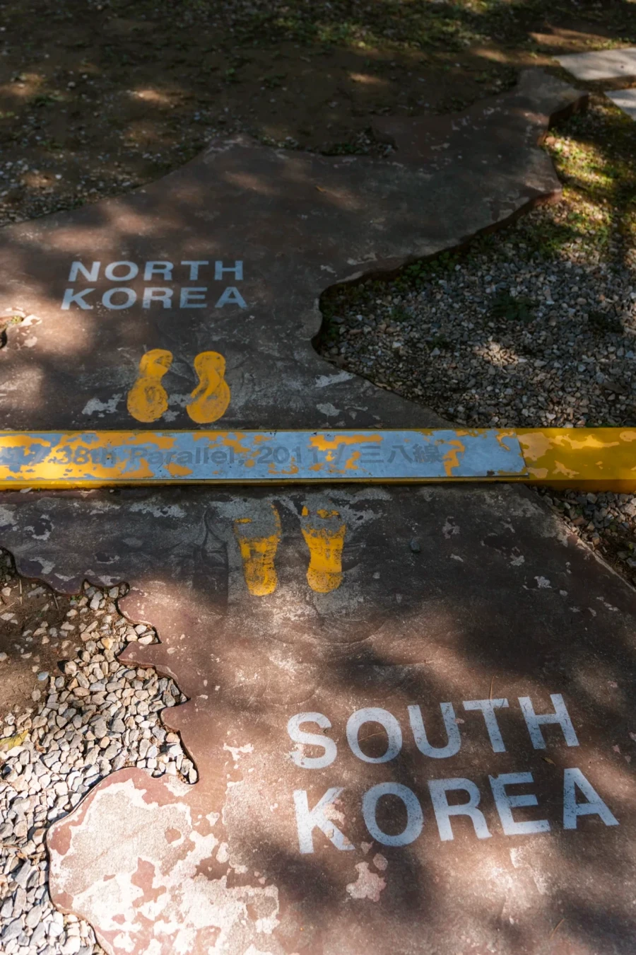 A stone path is labeled North Korea and South Korea on opposite sides of a yellow metal division