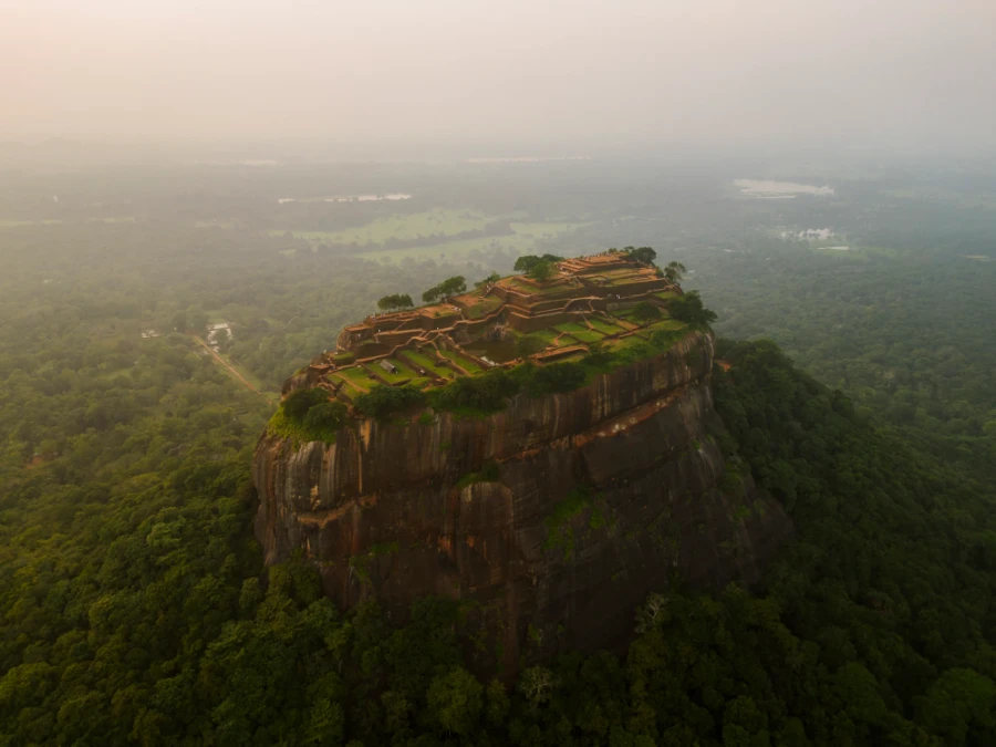 Ruins of an ancient palace atop a massive granite monolith that rises several hundred feet out of the jungle valley that surrounds it