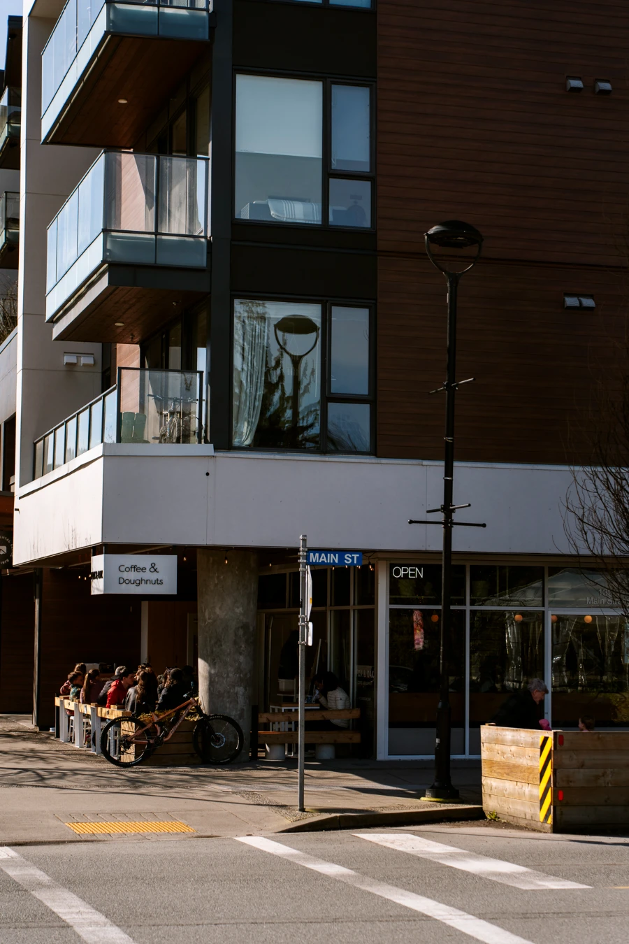 A street corner in downtown Squamish with a sign on the building in the corner lot that reads ‘Coffee & Donuts’