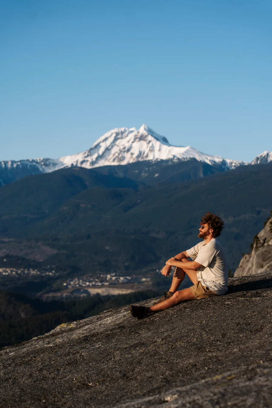 A man sitting on the bare granite cliff at first peak on Stawamus Chief