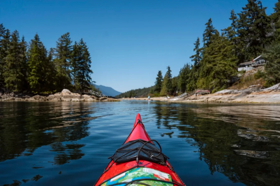 red kayak pointed towards a tree covered island in the Sechelt Inlet
