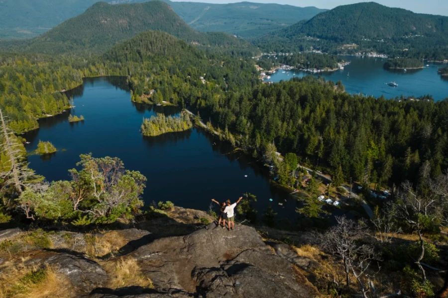 2 people stand on top of Pender Hill with their arms raised