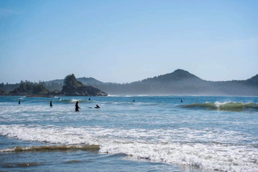 Crowds of surfers and instructors catching waves on a sunny day at Long Beach in Tofino, BC