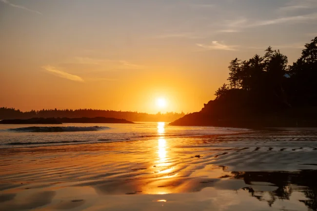 Sunset light reflected on wet sand at Tin Wis beach at sunset near Tofino, BC