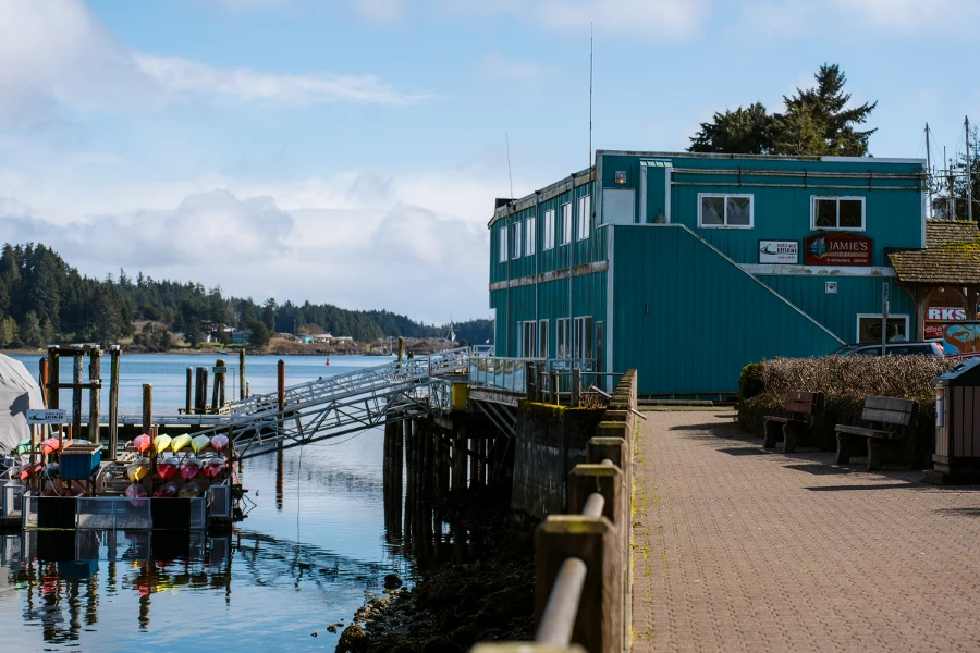 A stone boardwalk follows alongside the seaside and leads up to an old large wooden building